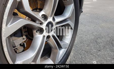The original alloy wheel, dirty and scratched on the car close-up. Worn car wheels are waiting for repair. selective focus. Car repair and restoration concept required. Damaged car wheel. Stock Photo