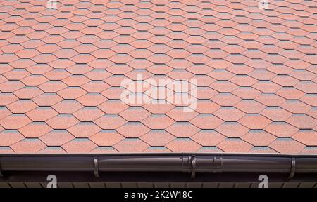 New roof with red shingles. Tiles on the roof of the house. Use to advertise roof fabrication and maintenance. Spotted texture. Affordable roofing. High quality photo with copy space. Stock Photo