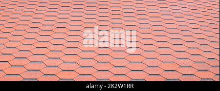 New roof with red shingles. Tiles on the roof of the house. Use to advertise roof fabrication and maintenance. Spotted texture. Affordable roofing. Banner with copy space. Stock Photo