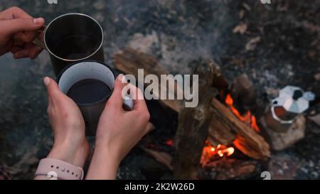 Couple in love Campsite With Fire Pit and Two Tin Cups with hot tea, coffee. Burning Campfire Stock Photo