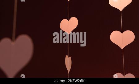 Flying red paper hearts on red dark background. Symbol of love. beautiful flying pink hearts. Happy Valentines Day. Stock Photo
