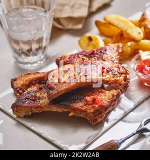 Closeup of pork ribs grilled with BBQ sauce and caramelized in honey. Grilled and smoked ribs with barbeque sauce on a carving board. Stock Photo