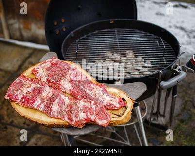 Raw hanging tender or onglet steak of beef on wooden Board. Preparing meat for barbecue grilling. BBQ. Stock Photo