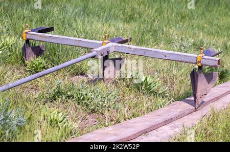 Agricultural manual metal plow on the field. Plowing the land before sowing. Close-up. Inventory for plowing potatoes in the countryside. A plow is a tool for plowing dense soil, raising virgin soil. Stock Photo