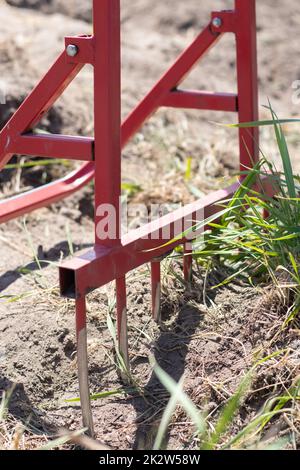 Red shovel in the form of a fork in the garden. Miracle shovel, handy tool. Manual cultivator. The cultivator is an effective tool for tillage. Bed loosening. Sustainable agricultural tools. Stock Photo