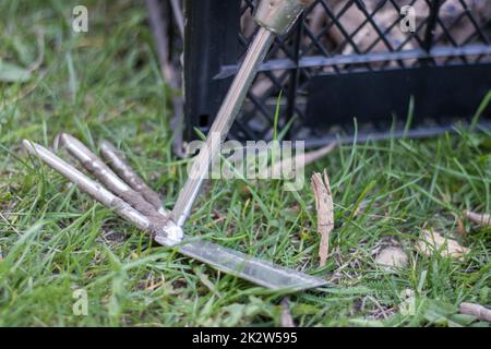 Garden tool rake chopper for gardening on the background of plastic boxes. The concept of gardening and sustainable summer. Metal garden tool with a rake and a hoe on a natural background. Stock Photo