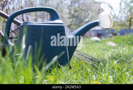 Blue plastic pot for watering in the garden. Can water. Watering can for flowers on the street, in the garden or garden on a warm summer sunny day. Stock Photo