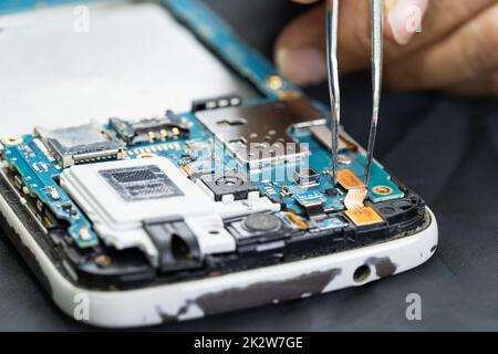 Technician repairing inside of mobile phone by soldering iron. Integrated Circuit. the concept of data, hardware, technology. Stock Photo