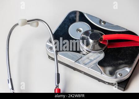 Red stethoscope with internal hard disk drive hdd contains health record and sensitive patient data with hardware doctor checkup and rest before data loss on faulty storage system or encryption breach Stock Photo
