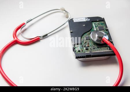 Red stethoscope with internal hard disk drive hdd contains health record and sensitive patient data with hardware doctor checkup and rest before data loss on faulty storage system or encryption breach Stock Photo