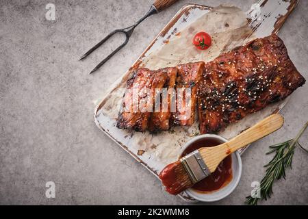 Delicious barbecued ribs seasoned with a spicy basting sauce and served on chopping board. Stock Photo