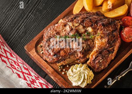 Ribeye steak with potatoes, onions and baked cherry tomatoes. Juicy steak with flavored butter Stock Photo