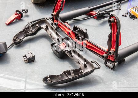 A man is repairing a battery-powered lawnmower. The electric toggle switch to start the engine is defective and needs to be replaced. A craftsman at work. Stock Photo