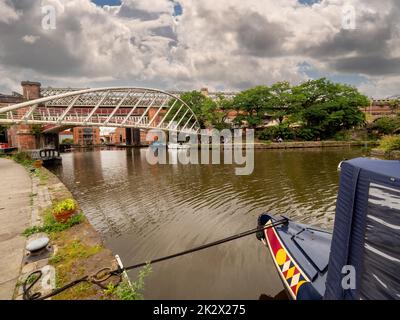 Bow of a moored narrowboat with Merchant's bridge in the distance, shot from the Bridgewater canal tow path. Manchester. UK. Stock Photo