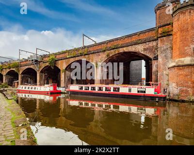 Canal cruise boats moored alongside the Bridgewater viaduct in the Castlefield area of Manchester. UK Stock Photo