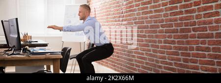 Businessman Doing Exercise In Office Stock Photo