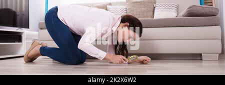 Woman Looking At Hardwood Floor Through Magnifying Glass Stock Photo