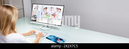 Female Dentist Video Conferencing With Her Colleagues On Computer In Clinic Stock Photo