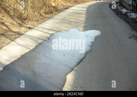 Puddle on asphalt. Wet road. Spilled water on pedestrian zone. Stock Photo