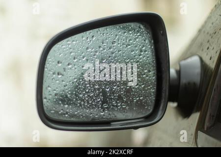 Wet rear-view mirror. Drops on glass. Transport in rain. Stock Photo