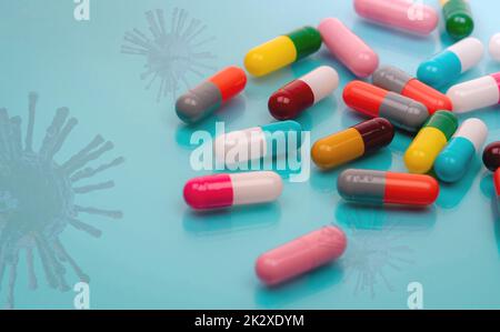 Antiviral capsule pills with virus on blue background. Drug development and new drug research for treatment emerging infectious diseases. Prescription drugs. Pharmaceutical industry. Pharmacology. Stock Photo