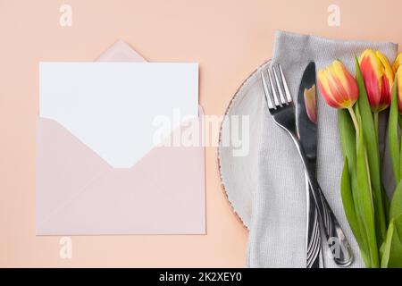 Mockup of a festive invitation in an envelope and a festive table setting. Stock Photo
