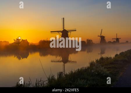 Traditional Dutch windmills with a colourful sky just before sunrise in Kinderdijk, The Netherlands Stock Photo