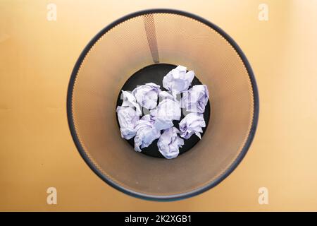 crumpled paper ball in a bin on orange color background top view  Stock Photo