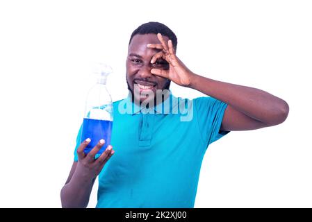 handsome young man with bottle of liquid soap, making correct gesture and looking through fingers smiling. Stock Photo