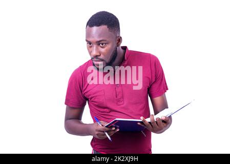 portrait of handsome serious young man holding open notebook with pen and looking aside. Stock Photo