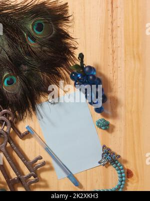 Notepaper and Pen on Table Surrounded By Peacock Feathers and Jewelry Stock Photo