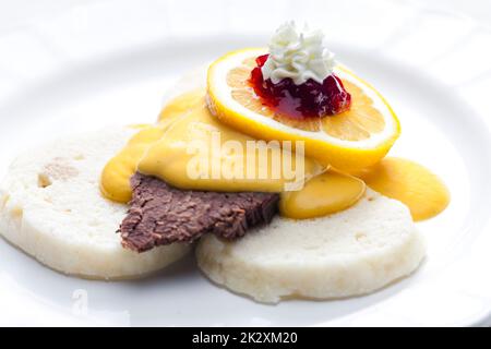 sirloin cream sauce with dumplings served with lemon, cranberries and whipped cream Stock Photo