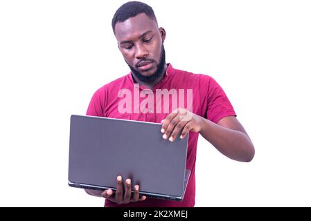 young businessman wearing red t-shirt standing on white background working using laptop. Stock Photo