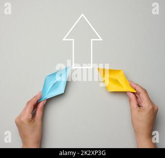 Two yellow-blue paper boats in female palms on a gray background. Ukraine support concept Stock Photo