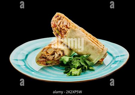 Shawarma of chicken in garlic lavash lies on a plate on a black isolated background Stock Photo