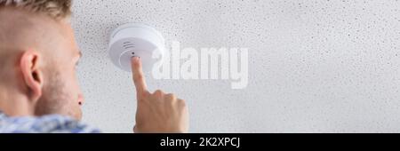 Person's Hand Installing Smoke Detector On Ceiling Stock Photo