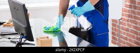 Janitor Cleaning Desk With Cloth In Office Stock Photo