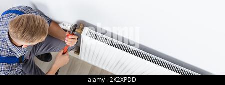 Male Plumber Fixing Thermostat Using Wrench Stock Photo