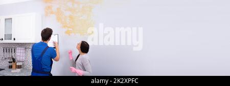 Worker Writing On Clipboard With Woman Standing Stock Photo