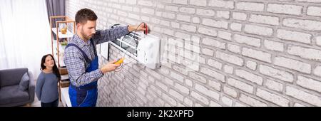 Technician Examining Air Conditioner With Digital Multimeter Stock Photo
