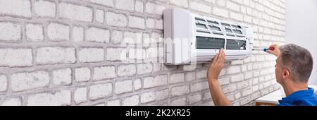 Technician Fixing Air Conditioner Stock Photo