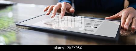 Businessperson Analyzing Invoice On Digital Tablet Stock Photo