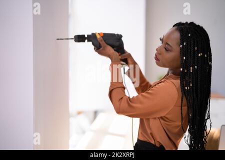 Woman Making Hole With Drill Machine Stock Photo