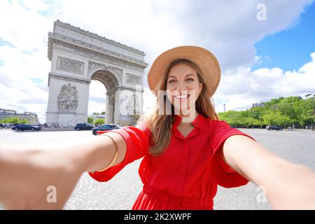 Happy young traveler woman taking selfie photo with Arc de Triomphe in Paris, France Stock Photo