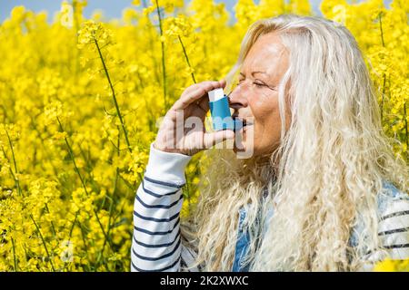 Woman with inhaler having asthma attack on spring day Stock Photo