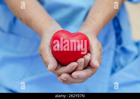 Asian elder senior woman patient holding red heart in hospital. Stock Photo