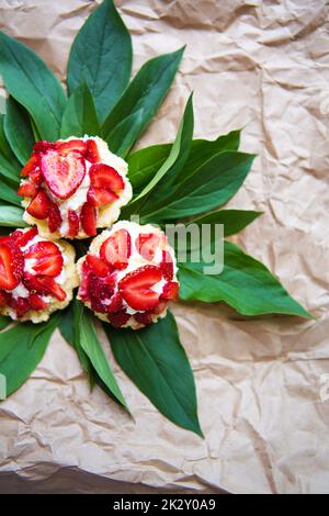 Beautiful and bright cupcakes with strawberries lie on green leaves, close-up Stock Photo