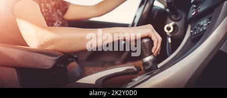 Woman driving a car and shifting gears on the gearbox. Stock Photo