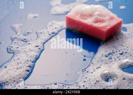 Sponge on wet soapy surface Stock Photo