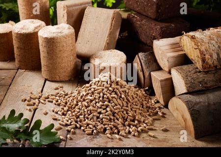 Pellets with woodpile and various biofuel briquettes on wooden table Stock Photo